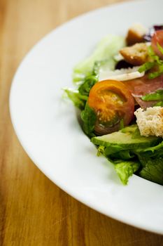 Side salad on the plate (tomato, cucumber, bread, parmesan, ham)