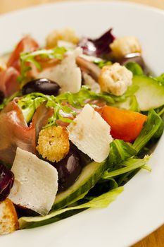 Side salad on the plate (tomato, cucumber, bread, parmesan, ham)