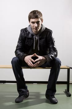 Portrait of a handsome young man sitting on the bench