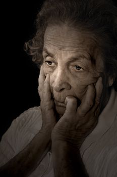Dark and dramatic portrait of an old woman thinking with anguish on painful memories