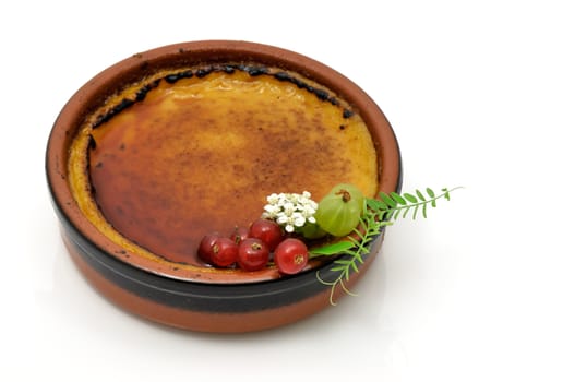 French creme brulee served in an earthenware dish and decorated with small fruits