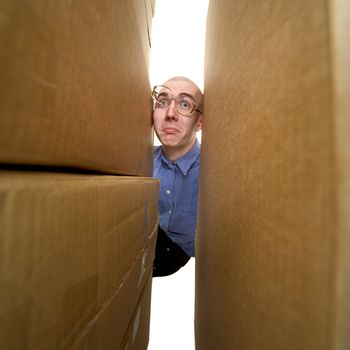 Male face between pile cardboard boxes on white