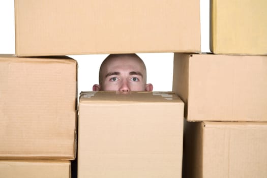 Male face in pile ofcardboard boxes on a white