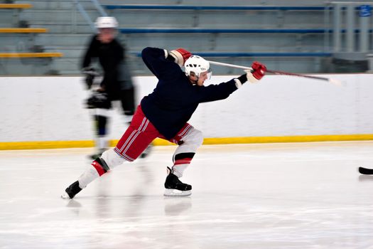 A hockey player shooting the puck as he speeds down the ice.  Slight motion blur.