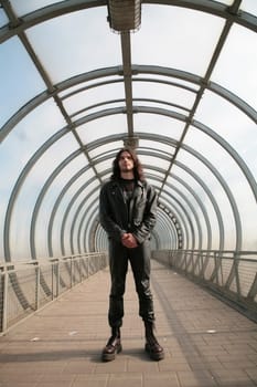 man in leather gothic cloth in blue transparent tunnel from glass