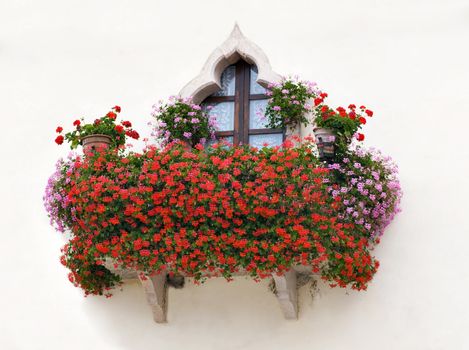 An Italian house balcony with pink and red flowers