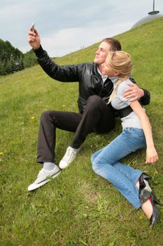gay in black jacket shows device to blond girl