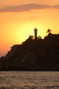 Silhouette of lighthouse and palms during sunset over the beach of Puerto Escondido