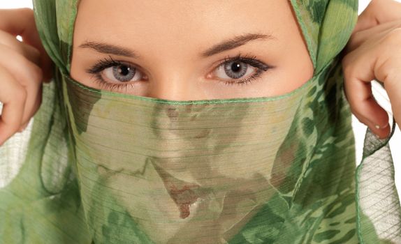 Young arab woman with veil showing her eyes isolated on white background.