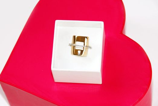 golden ring gift in white box over red heart background