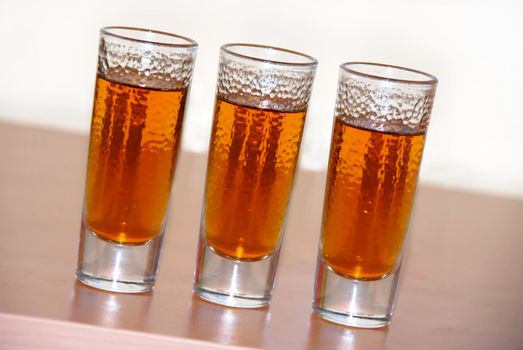 three small glasses of brown alcohol drink closeup