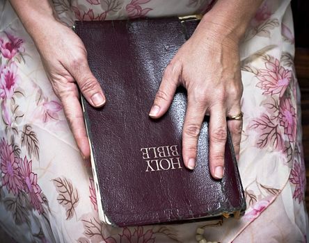 woman lovingly holding a Bible in her lap

