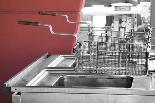 Double used restaurant fryer in open space by a red wall