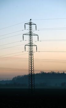 Landscaoe with silhouette of electric pylon during sunset