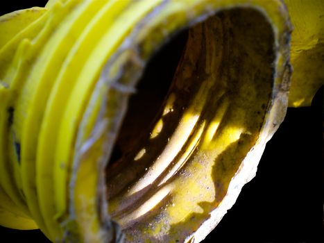 Old yellow used plastic bottle on a black background