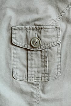 Extreme closeup of khaki jacket pocket closed with button