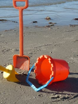 Kid's bucket and spade on wet sand in evening light