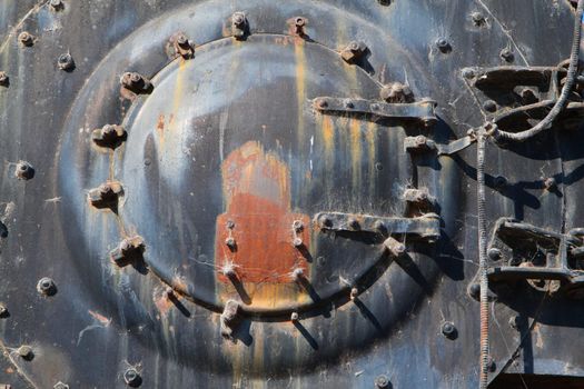 Rusted brightly lit boiler cap on front end of railroad engine