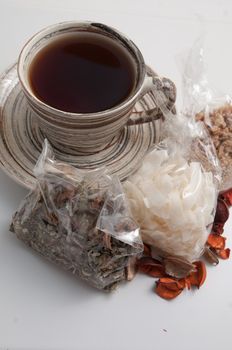 A cup of tea and herbs on the white background .