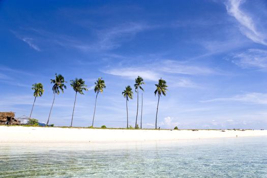 Image of a remote Malaysian tropical island with deep blue skies, crystal clear waters, atap huts and coconut trees.