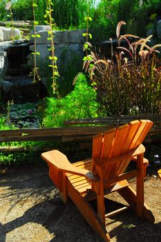 Natural stone pond and patio landscaping with wooden chair