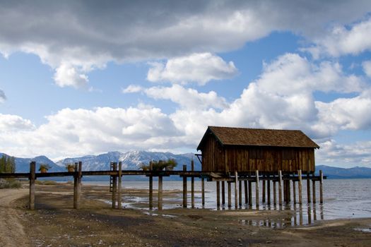 Landscape of wooden jetty extending out, dramatic clouds and mountains in background