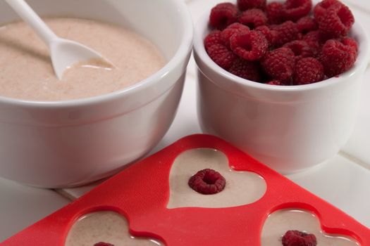 Batter bowl and raspberries with heart shaped muffin pan