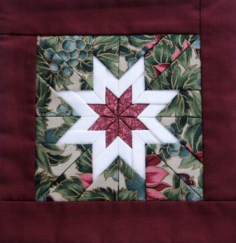 quilted star in white with colorful fabrics and a maroon border