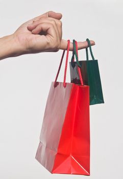 Detail of hand holding two Christmas shopping bags against white background