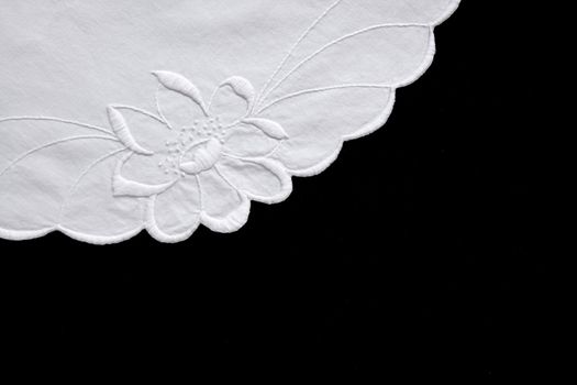 embroidered white flower on fabric with scalloped edges isolated on black