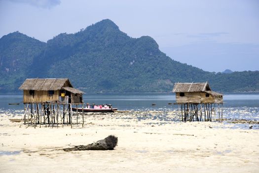Image of native huts on stilts and a house boat.