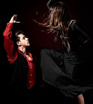 High contrast Young couple passion flamenco dancing on red light background.