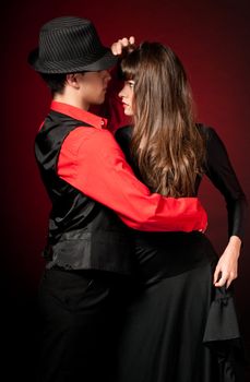 Young couple passion dancing and embracing on red light background.