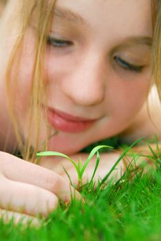 Closeup on a face of a young girl watching a new seedling grow