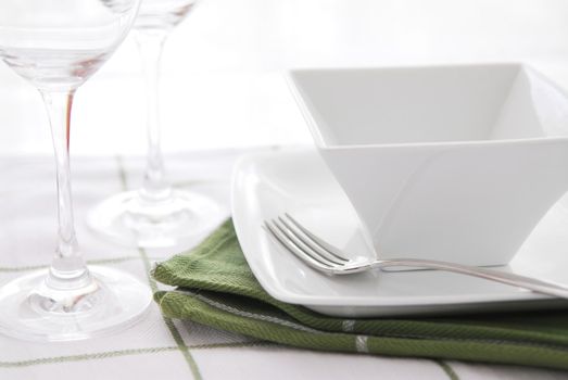 Place setting with white dishes and wine glasses