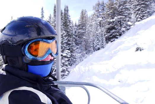 Young girl in downhill ski gear on a chairlift at ski resort