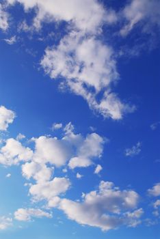 Background if bright blue sky with white fluffy clouds