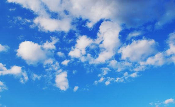 Background if bright blue sky with white fluffy clouds