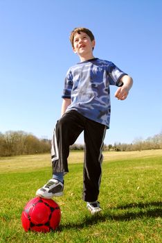 Young cute happy boy with a red soccer ball outside