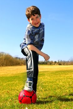 Portrait of a young boy with a red soccer ball outside