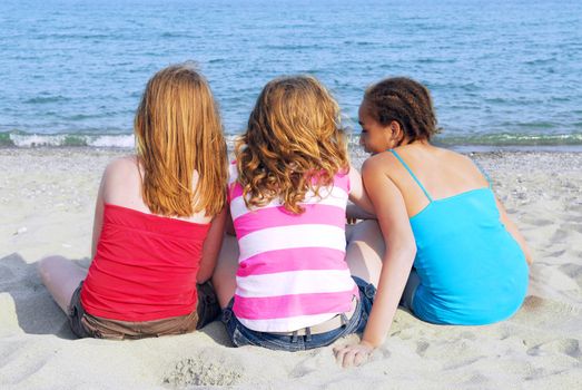 Portrait of three teenage girls sitting on a sandy beach