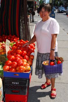 Attractive mature woman buying vegetables at fruit stand