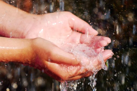 Hands catching clean falling water close up. Environmental concept.