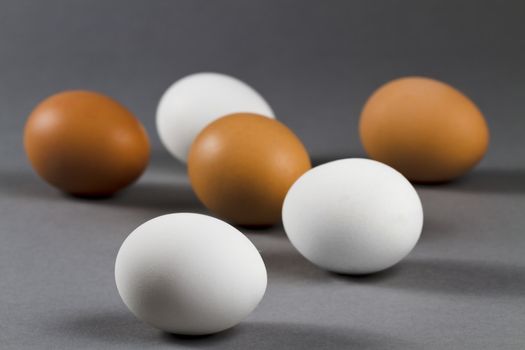 three white and three brown eggs on grey background