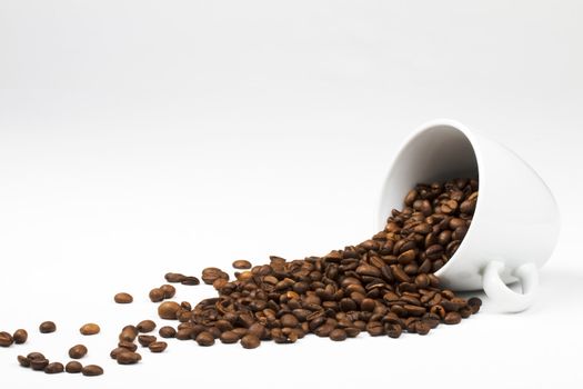 some coffee beans falling from a coffee cup on white background