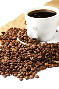 coffeebeans near coffee cup and jute on white background