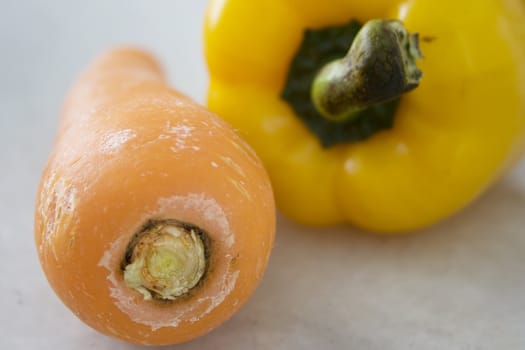 Close up of a carrot and a yellow pepper.