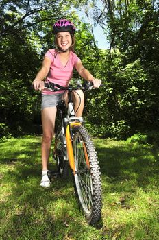 Portrait of a teenage girl on a bicycle in summer park outdoors