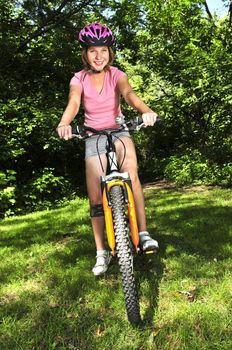 Portrait of a teenage girl on a bicycle in summer park outdoors