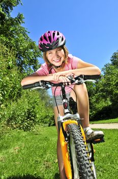 Portrait of a teenage girl on a bicycle in summer park outdoors